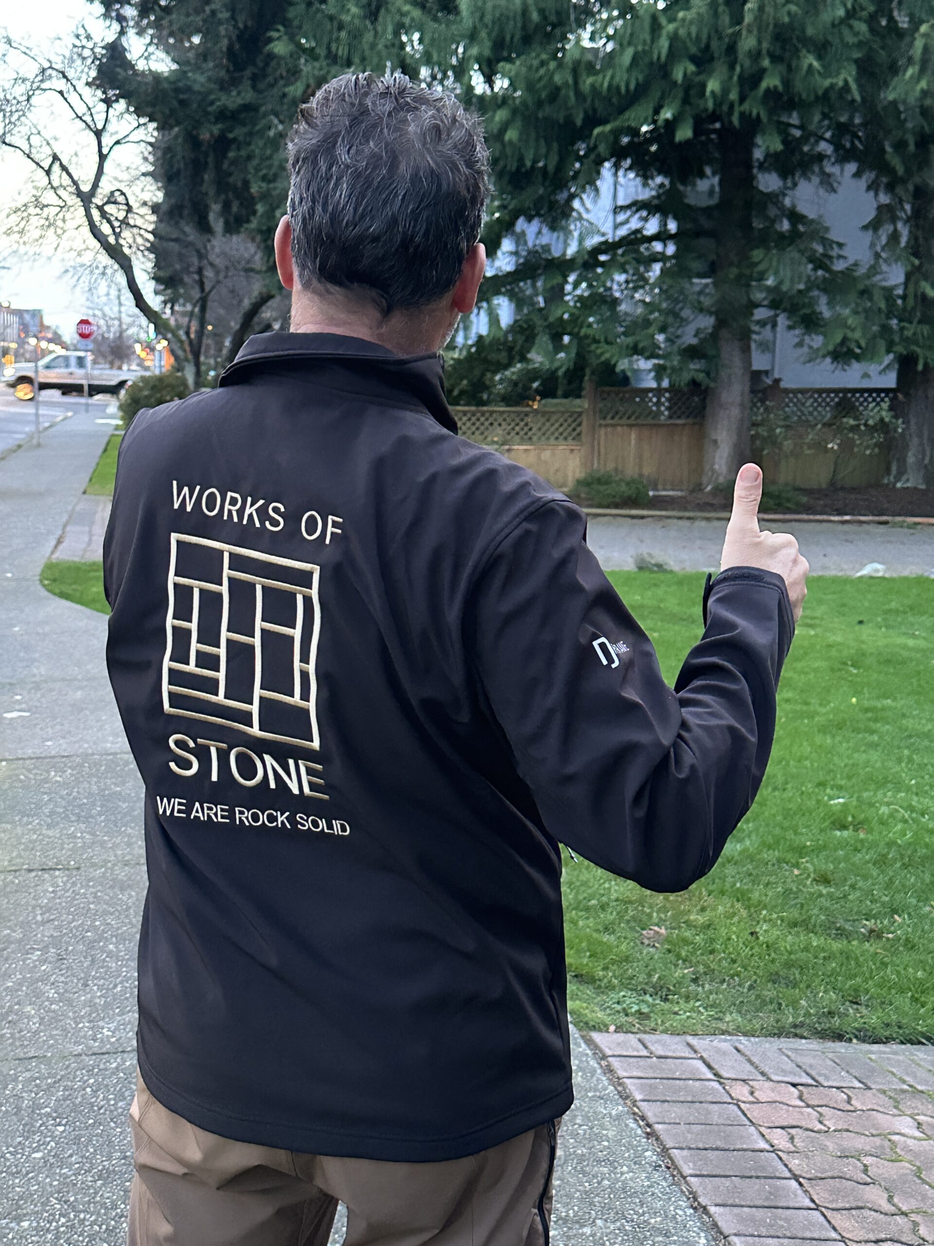 A man is wearing a "Works of Stone" company jacket